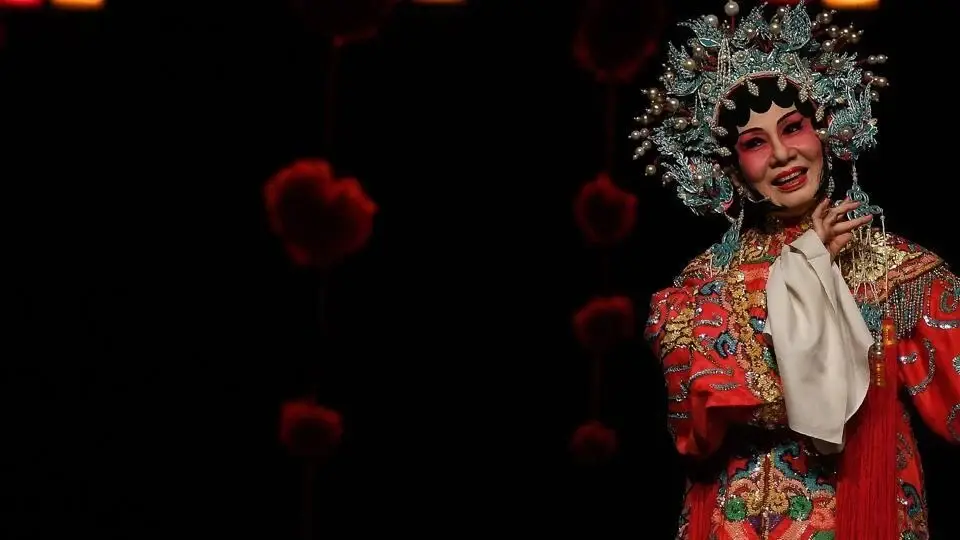 Cantonese opera leads on stage in embroidered costumes amid purple light