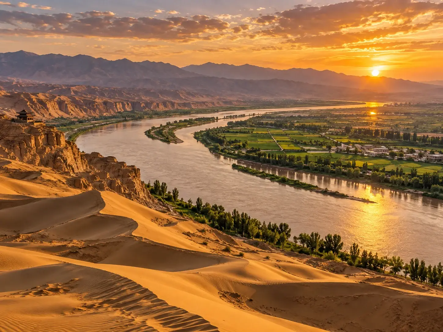 Ningxia at sunset — golden sand dunes above a great bend of the Yellow River, green irrigated oasis farmland along the banks, arid mountains beyond and a small pavilion on the cliff