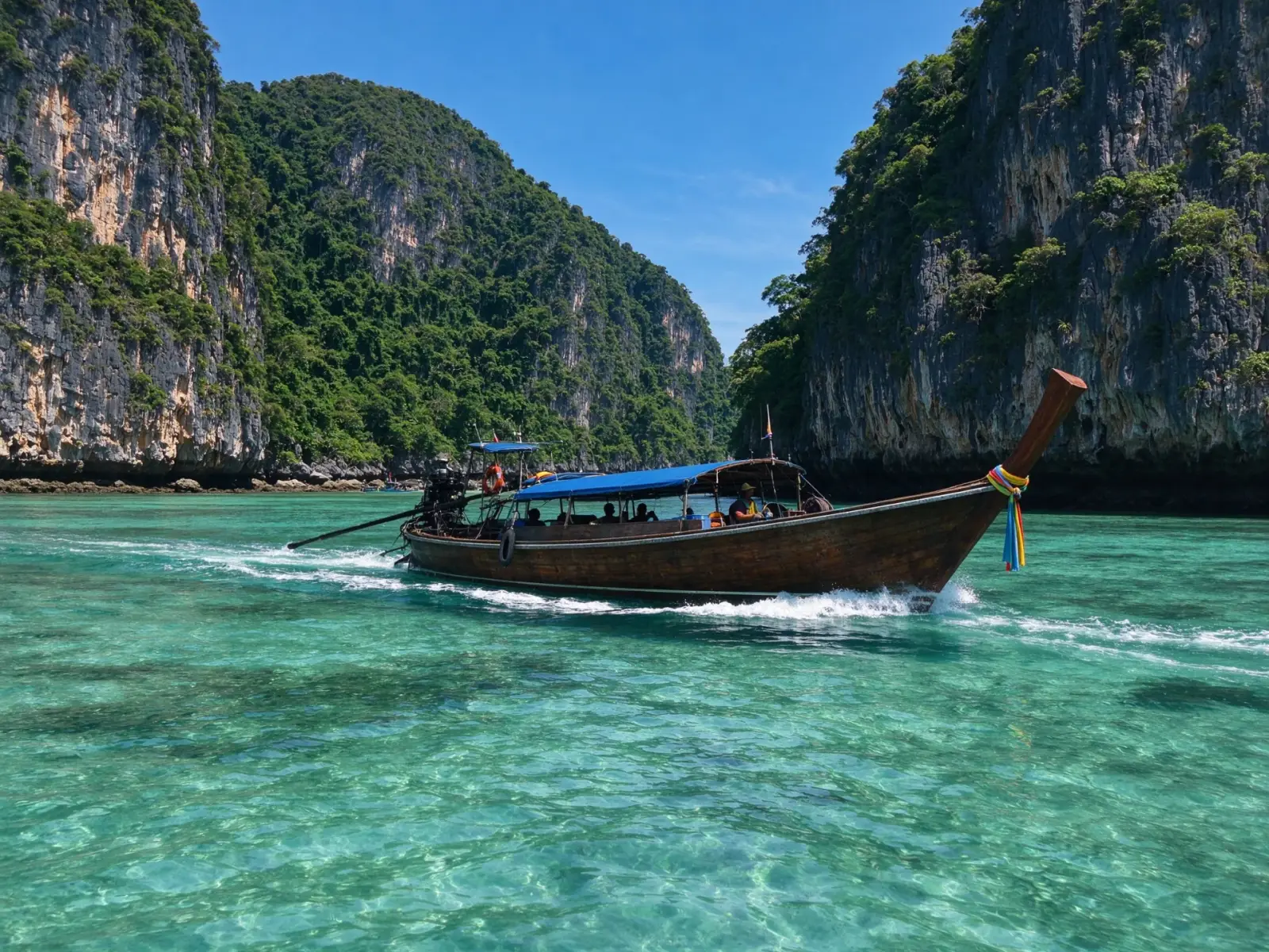 Long-tail boats, clear water and limestone cliffs on a Thai island