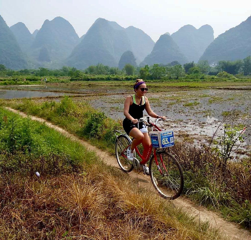 A woman cycling beside karst fields