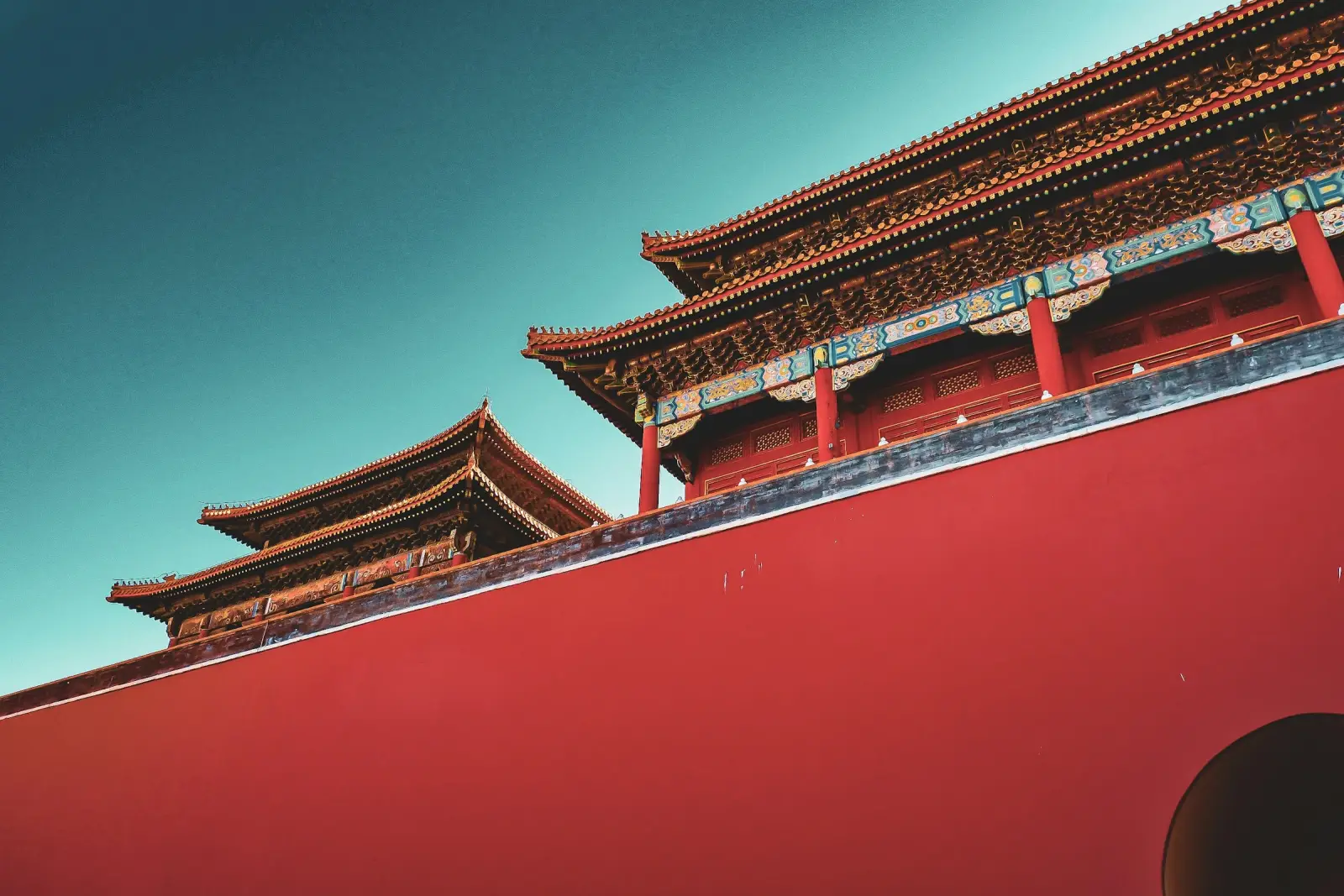 Red walls and golden eaves of the Forbidden City against a turquoise sky