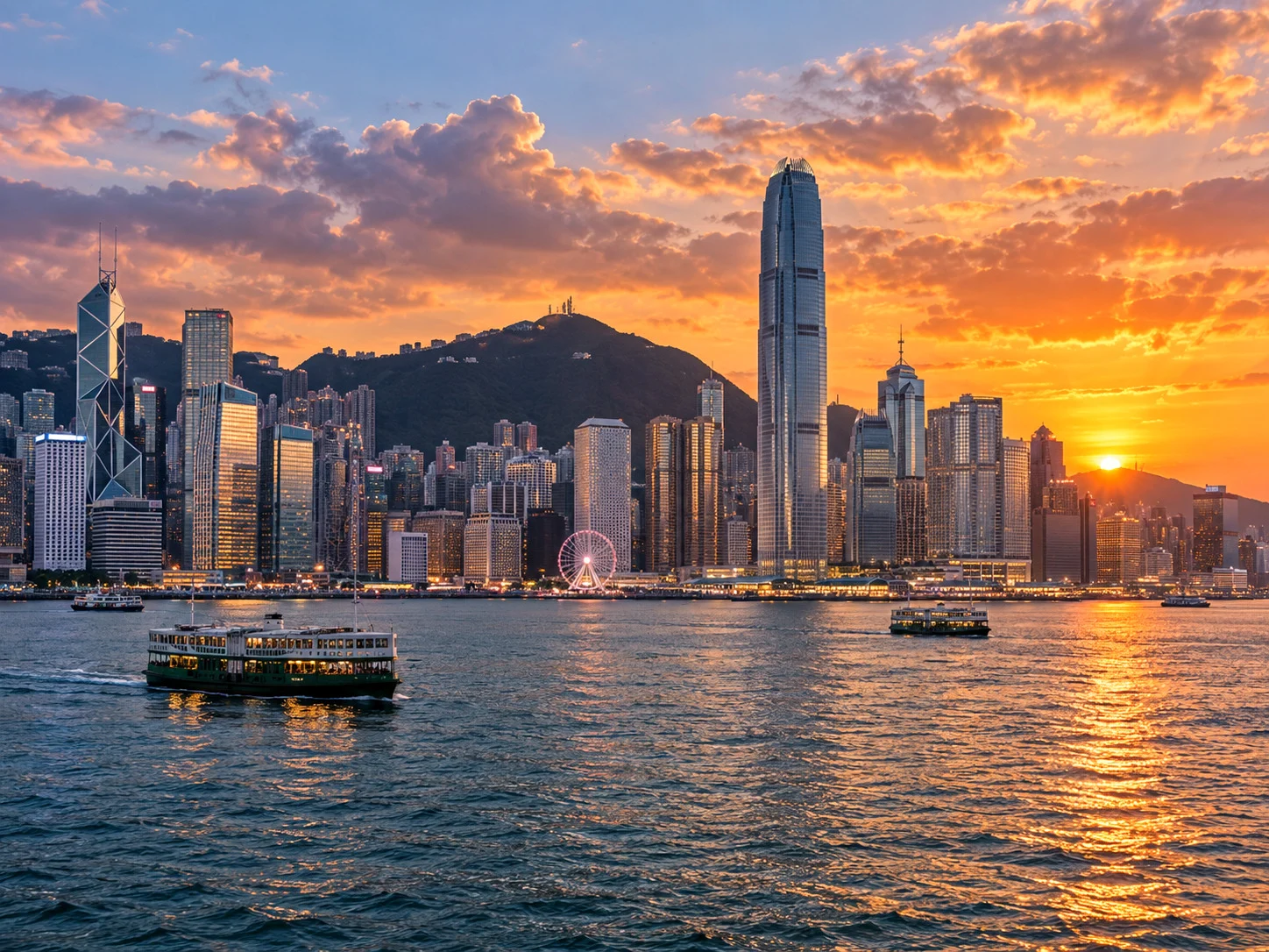 Sunset over Victoria Harbour with a Star Ferry, the ICC and the Ferris wheel on the Hong Kong Island waterfront