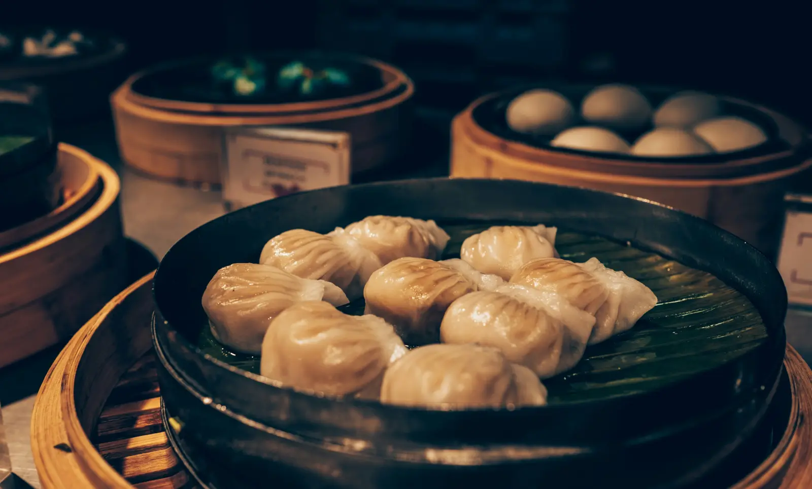 Chinese dumplings in a bamboo basket under warm restaurant lighting