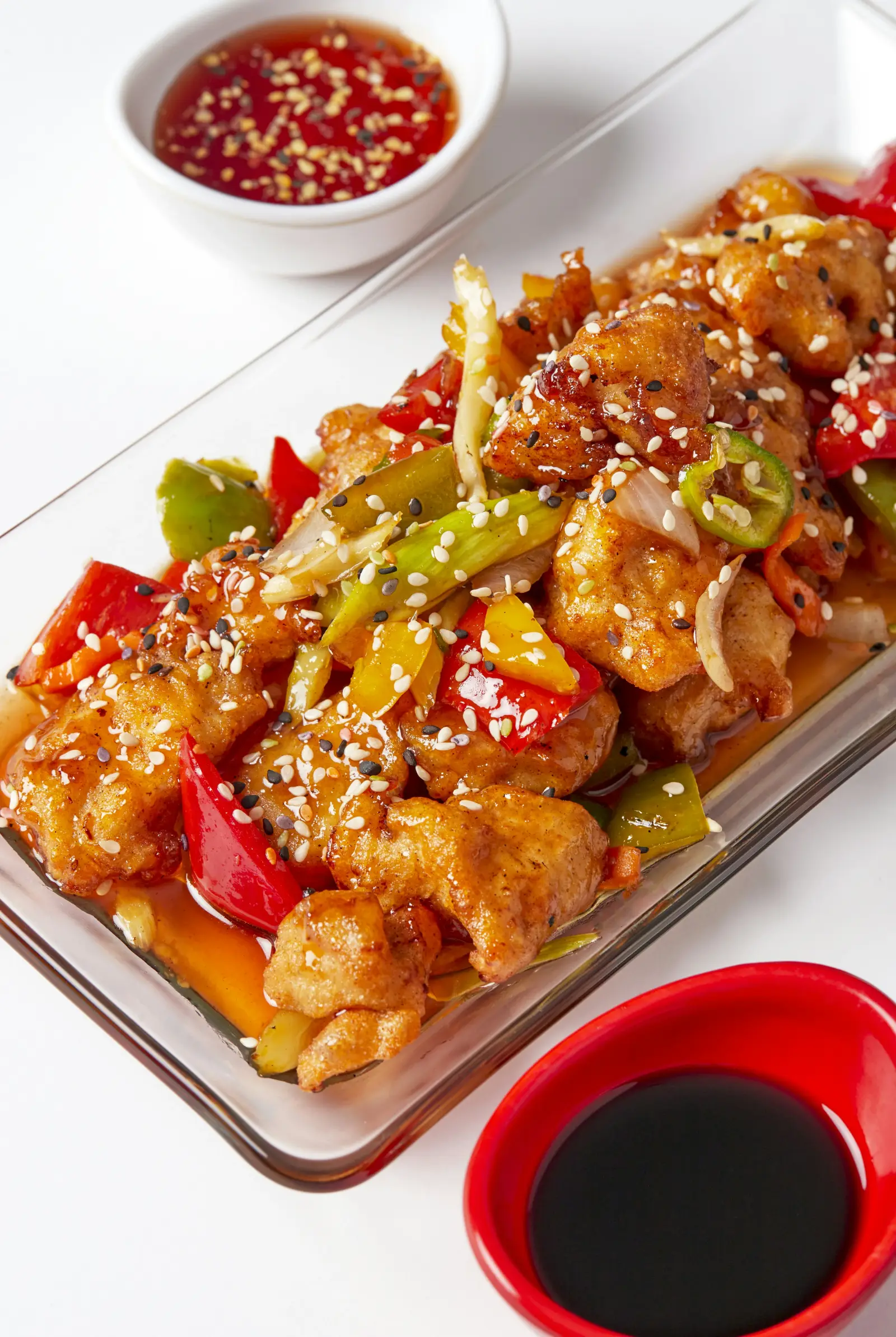 Chinese sweet and sour dish with colorful peppers and dipping sauce