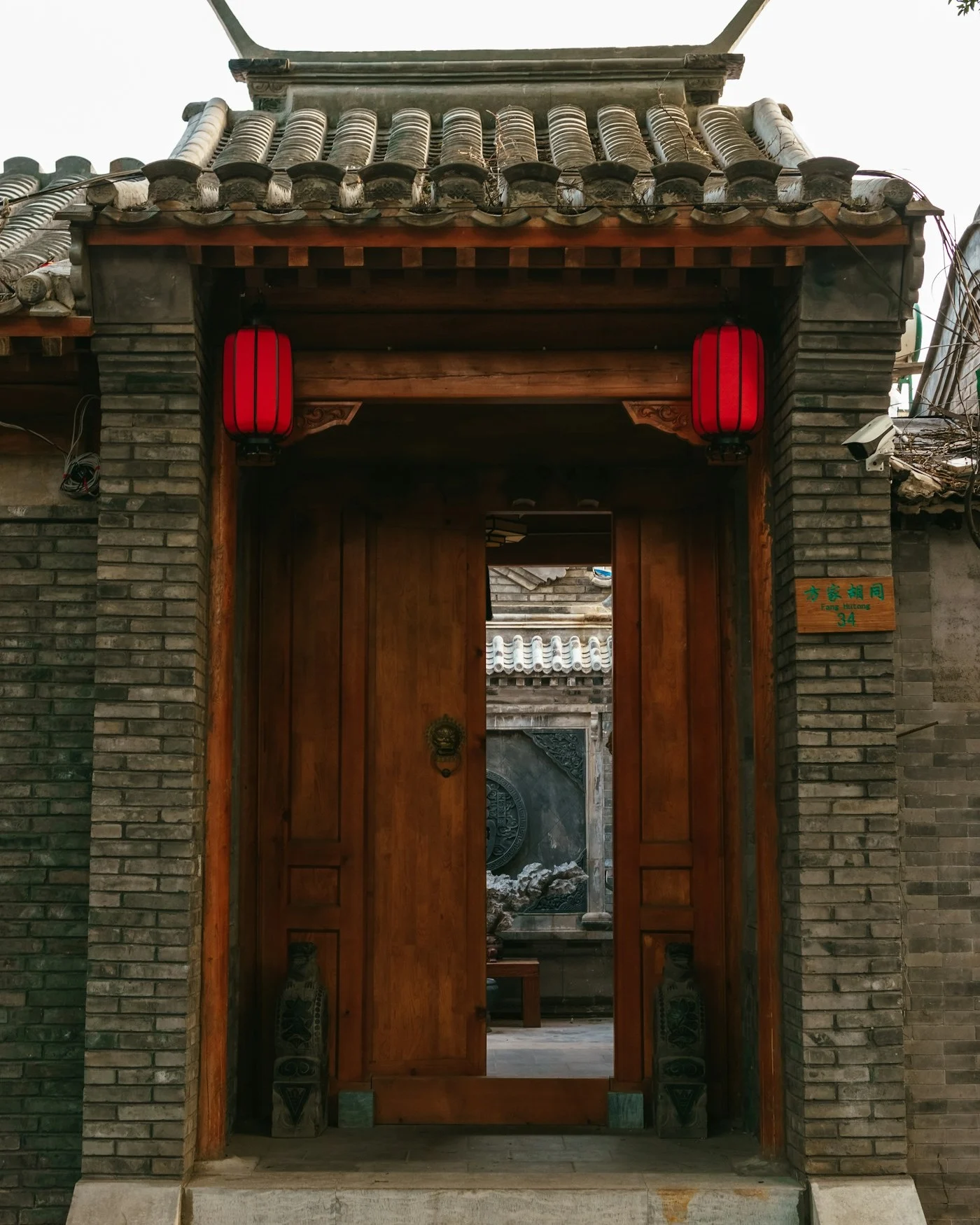 A figure walking through a snow-covered Beijing hutong at night